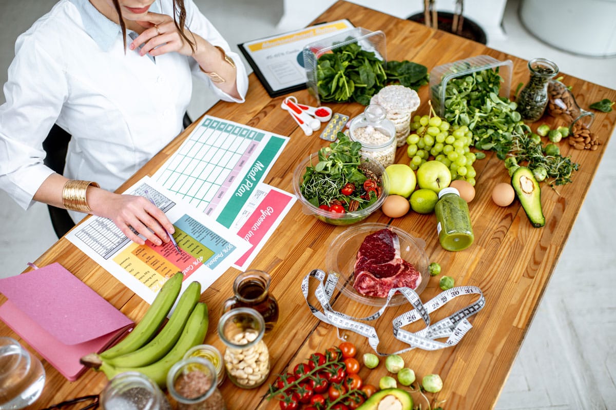 Rédaction d'un plan de régime sur la table pleine d'aliments sains