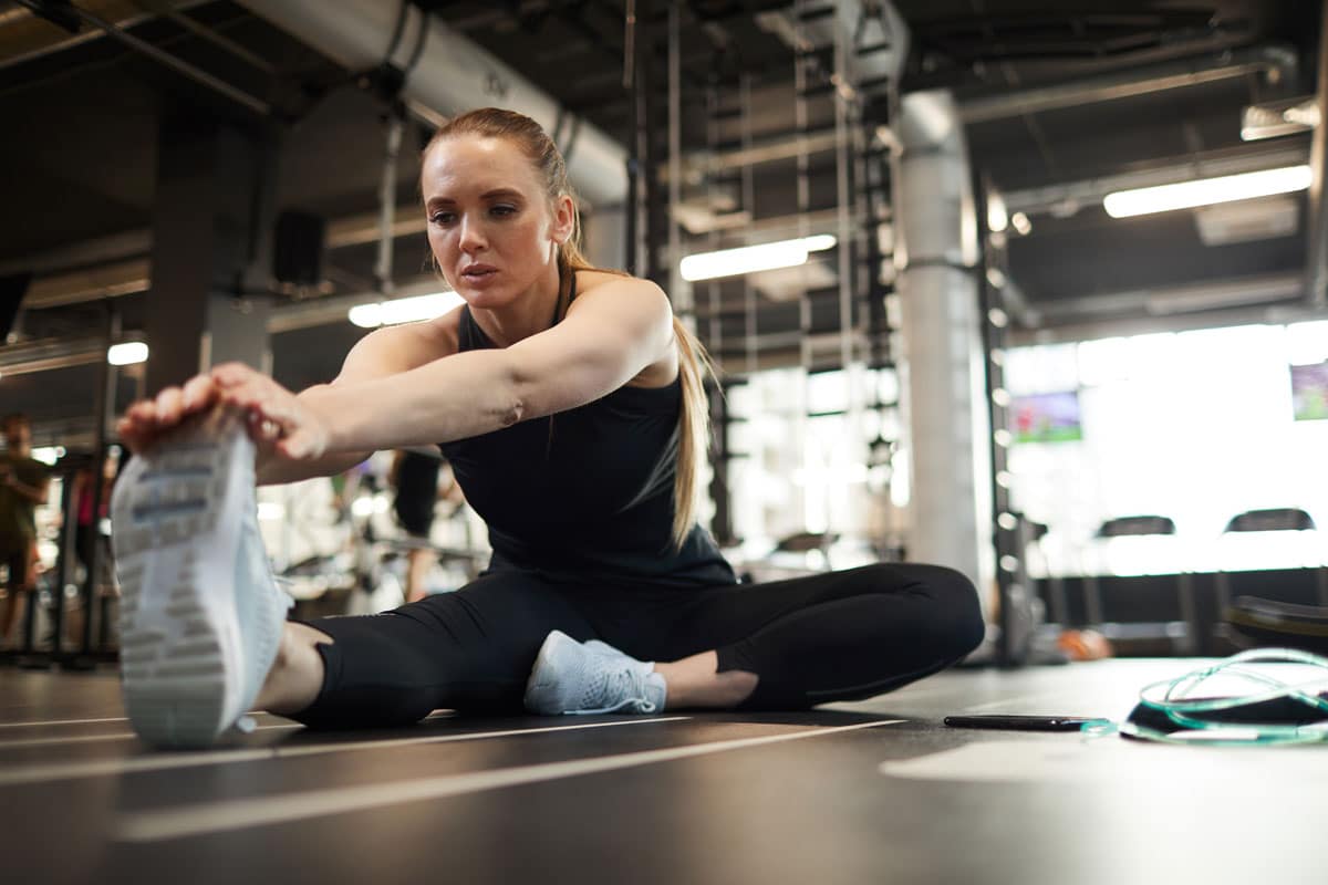 Femme faisant des exercices de stretching dans une salle de fitness