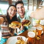 Couple heureux prenant un selfie avec des Burgers en vacances