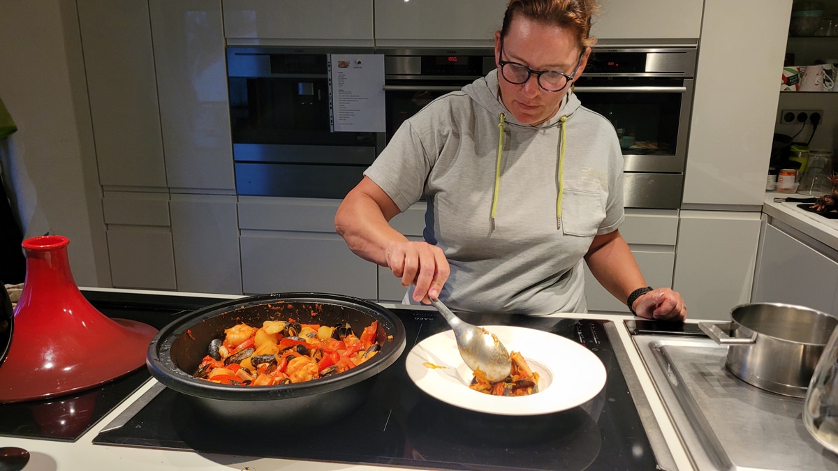 Elvi prépare une cataplana de poisson et crustacés dans une tajine.